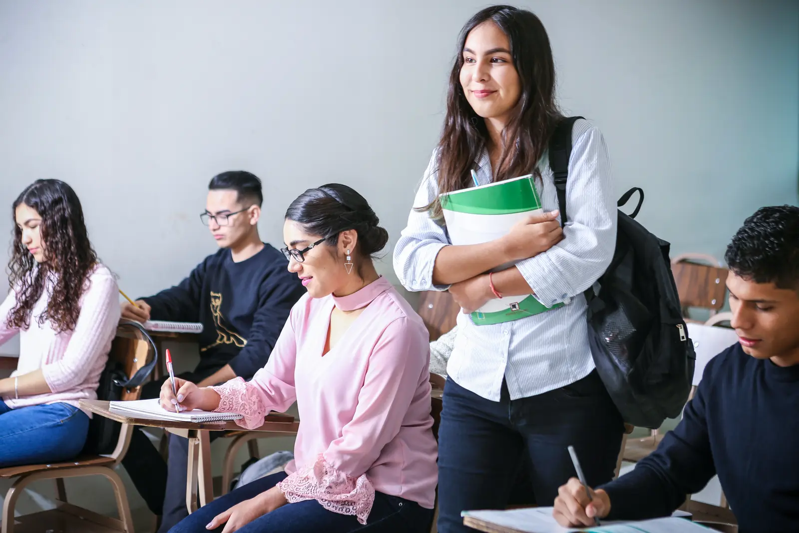 Des étudiants en classe, dont une jeune femme debout avec ses cahiers